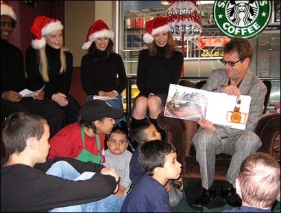 Solange Sandy, Bryn Dowling, Donna Marie Asbury and Michelle Potterf watch Huey Lewis read to a group of children at the kick-off of the Holiday Angles Joy Drive.